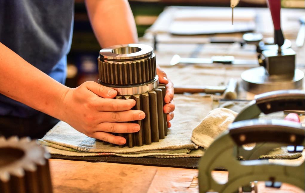 Ein Zahnrad einer Getriebeübersetzung. Es wird in den Händen eines Mitarbeiters gehalten.